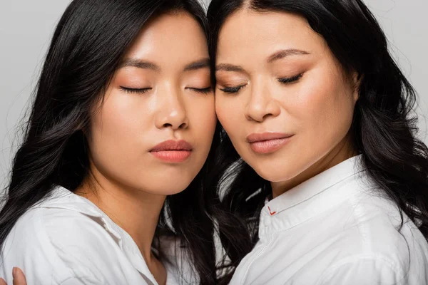 Asian mother and young adult daughter in white shirts isolated on grey — Stock Photo