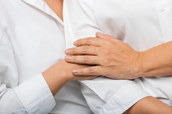 Cropped view of young daughter and mother in white shirts holding hands — Stock Photo