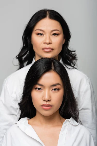 Brunette asian mother near young adult daughter isolated on grey — Stock Photo