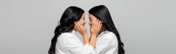 Side view of happy asian mother and young adult daughter touching cheeks of each other isolated on grey, banner — Stock Photo