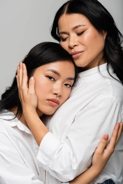 Premuroso asiatico madre abbraccio giovane figlia isolato su grigio — Foto stock