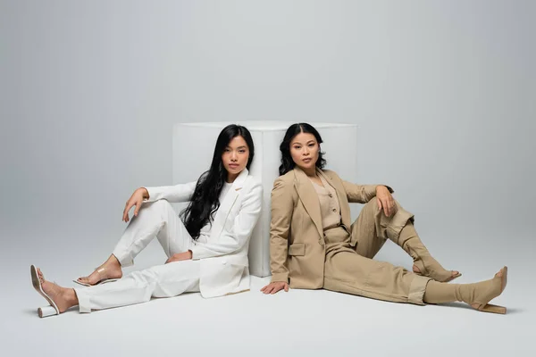 Volle Länge der asiatischen junge erwachsene Frau sitzt mit brünette Mutter in der Nähe Würfel auf grau — Stockfoto