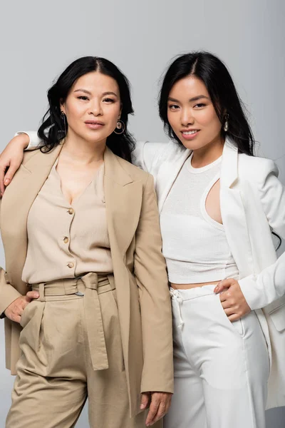 Fröhliche asiatische Mutter und Tochter umarmen isoliert auf grau — Stockfoto