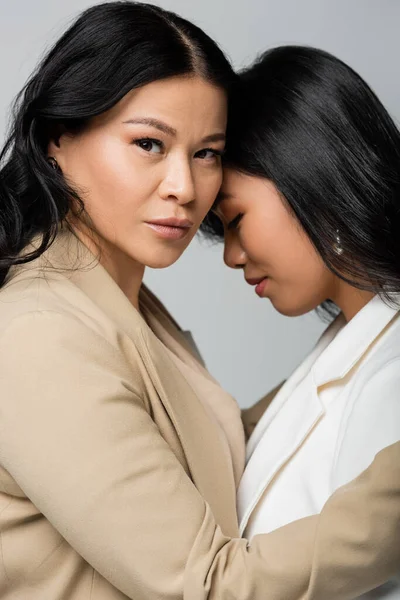 Азіатська мати обіймає дочку ізольовано на сірому — стокове фото