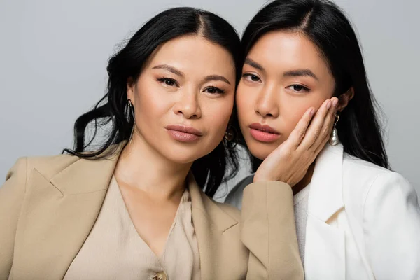 Asian mother touching cheek of young daughter isolated on grey — Stock Photo