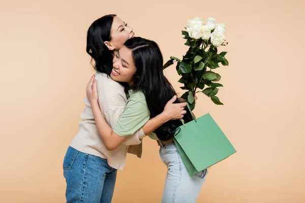 Feliz asiático filha congratulando e abraçando mãe isolado no bege — Fotografia de Stock