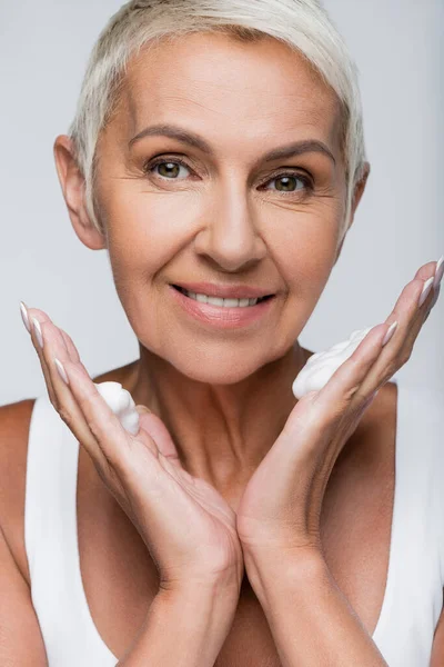 Glückliche Seniorin mit Reinigungsschaum auf den Händen isoliert auf grau — Stockfoto