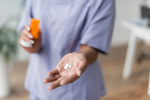 Vue recadrée de l'infirmière tenant des pilules dans la main — Photo de stock