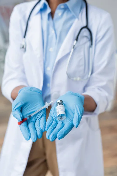 Vista recortada del médico sosteniendo el frasco con vacuna y jeringa en las manos - foto de stock