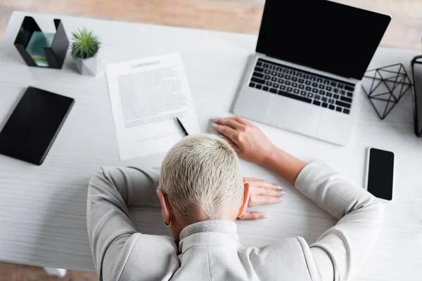 Draufsicht einer müden Geschäftsfrau mit grauen Haaren, die mit Gadgets und Dokumenten auf dem Schreibtisch liegt — Stockfoto
