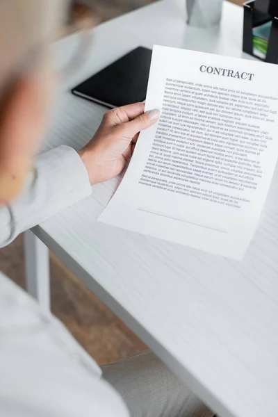 Blurred senior businesswoman holding contract in office — Stock Photo