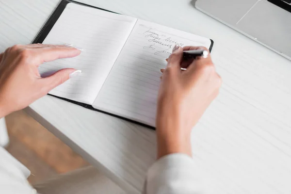 Vista recortada de la mujer de negocios escribiendo en el cuaderno con pluma - foto de stock