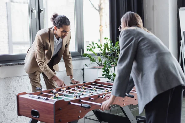 Empresária turva jogando futebol de mesa com jovem colega afro-americano no escritório — Fotografia de Stock