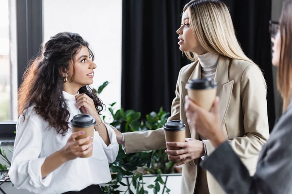 Mulheres de negócios jovens segurando copos de papéis enquanto fala durante pausa de café em ofice — Fotografia de Stock