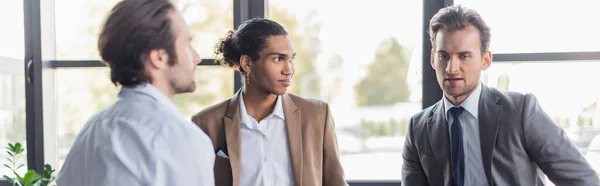 Young interracial business colleagues talking in office, banner — Stock Photo