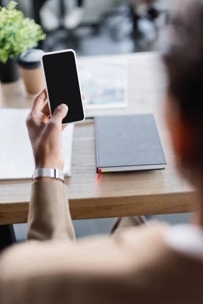 Vista cortada do empresário americano africano desfocado segurando smartphone com tela em branco — Fotografia de Stock