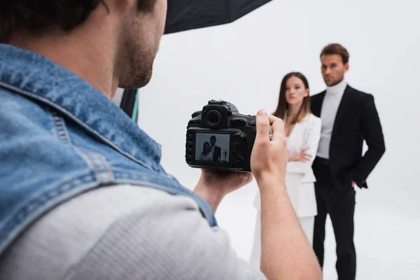 Professional photographer taking photo of blurred models on white — Foto stock