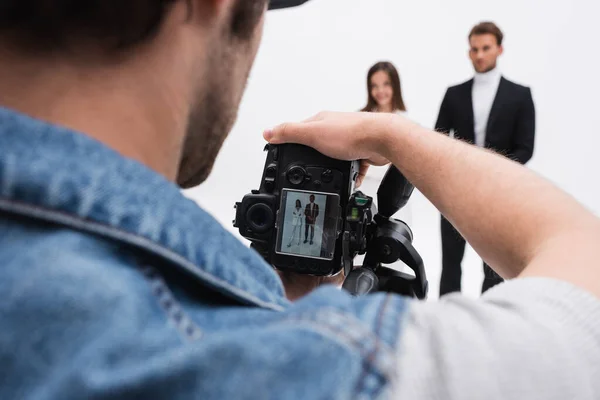 Photographer with digital camera taking photo of blurred models isolated on white — Stock Photo
