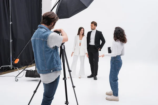 Art director talking to models near photographer during photo session — Foto stock