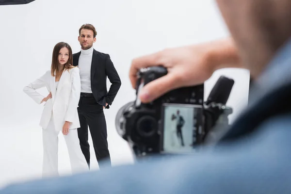 Verschwommene Fotografin arbeitet mit jungen und trendigen Models, die auf Weiß posieren — Stockfoto