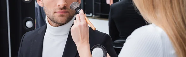 Partial view of visage artist applying face powder while doing makeup to man, banner — Fotografia de Stock