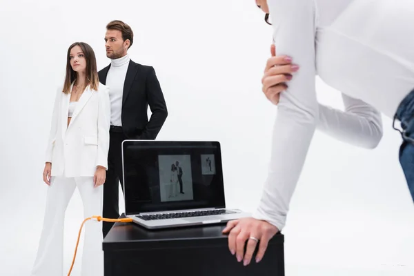 Direttore creativo vicino laptop e modelli alla moda posa isolato su bianco — Foto stock