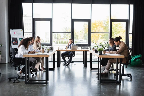 Businessman talking on mobile phone during meeting with multiethnic colleagues — Fotografia de Stock