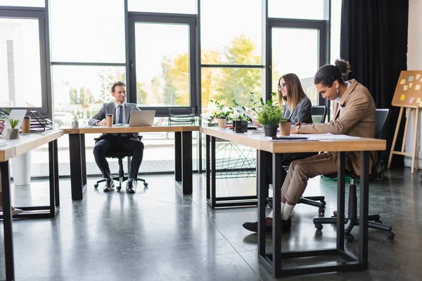 Giovani e sorridenti uomini d'affari multiculturali che lavorano in uffici moderni — Foto stock