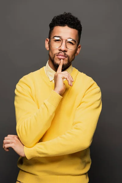 Pensive african american man in glasses looking at camera isolated on grey — Stock Photo