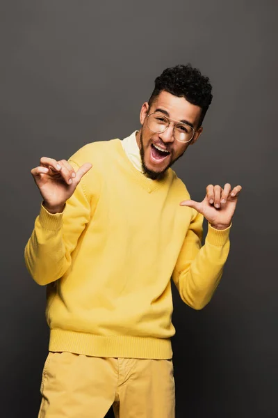 Amazed african american man in glasses pointing with thumb at himself isolated on grey — Stock Photo