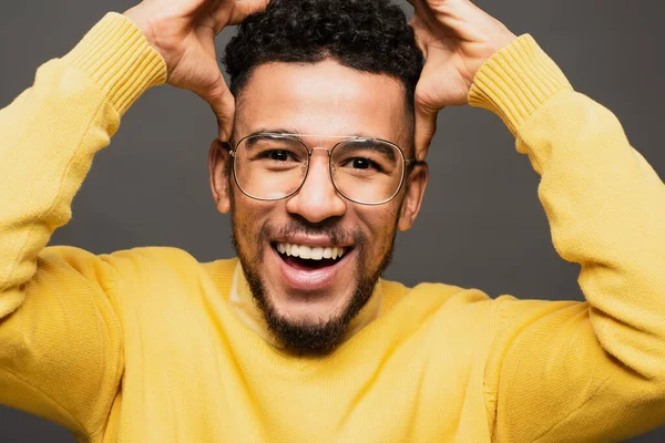 Amazed african american man in glasses smiling isolated on grey — Stock Photo