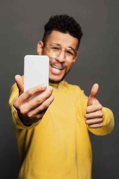 Homem americano Africano desfocado e positivo em óculos tomando selfie isolado em cinza — Fotografia de Stock