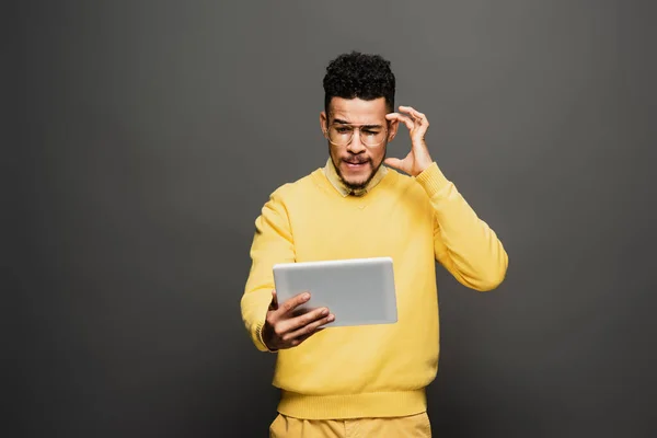 Homme afro-américain réfléchi dans des lunettes en utilisant une tablette numérique sur gris foncé — Photo de stock