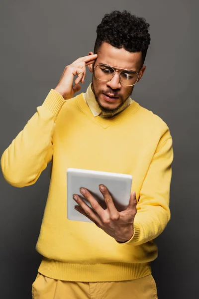Afrikanischer Mann in Brille mit digitalem Tablet isoliert auf grau — Stockfoto