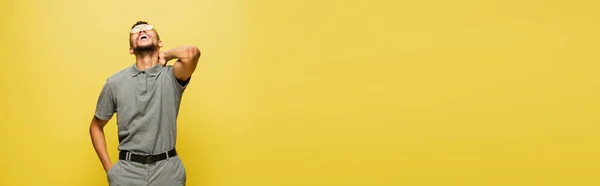 Fröhlicher afrikanisch-amerikanischer Mann mit Sonnenbrille und grauem Tennishemd lachend auf gelbem Banner — Stockfoto