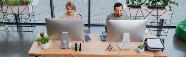 Vista de ángulo alto de colegas interracial que trabajan en la oficina moderna, pancarta - foto de stock