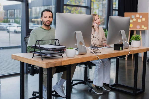 Uomo afroamericano guardando lontano vicino collega parlando sul cellulare — Foto stock