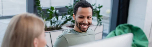 Glücklich afrikanisch-amerikanischer Mann schaut blonde Kollegin im Büro an, Banner — Stockfoto