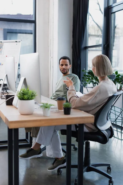 Afrikanisch-amerikanischer Manager schaut blonde Kollegin im Büro an — Stockfoto