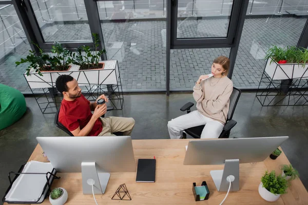 Vista de ángulo alto de colegas interracial mirándose en la oficina moderna - foto de stock