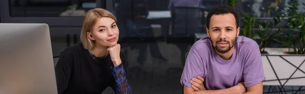 Young interracial colleagues looking at camera, banner — Stock Photo