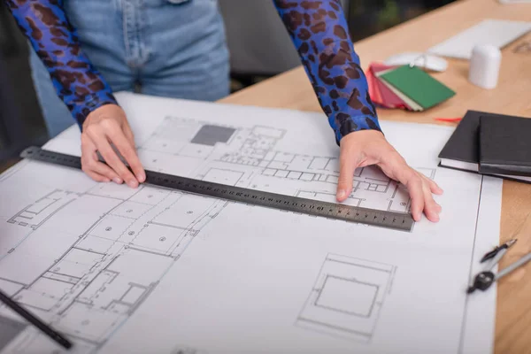 Cropped view of interior designer holding ruler while working with blueprint — Stock Photo