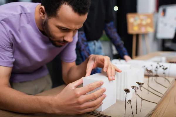 African american architect collecting house model near blurred colleague — Stock Photo