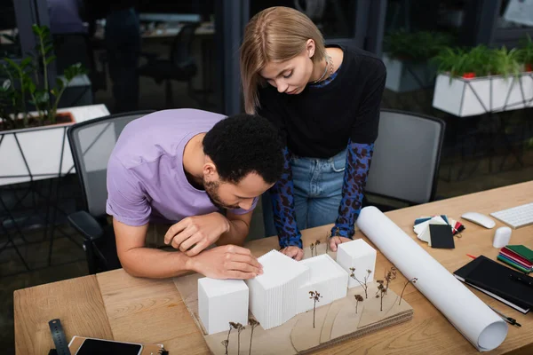 Jeunes architectes multiethniques travaillant avec le modèle de maison en carton dans le bureau — Photo de stock