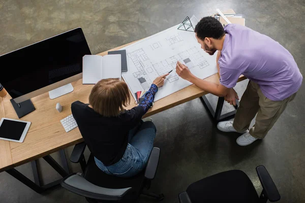 Top view of multiethnic interior designers discussing blueprint near color samples — Stock Photo