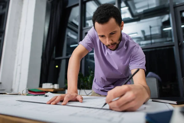 Focused african american architect holding pencil and ruler near blueprint — Stock Photo
