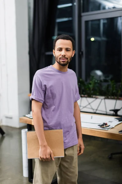 Молодий афроамериканський менеджер тримає блокнот в сучасному офісі — стокове фото