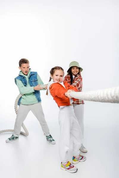 Дети-подростки тянут веревку, играя в перетягивание каната на белом — стоковое фото