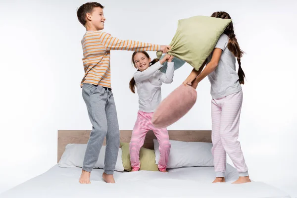 Bambini gioiosi avendo lotta cuscino mentre in piedi isolato su bianco — Foto stock