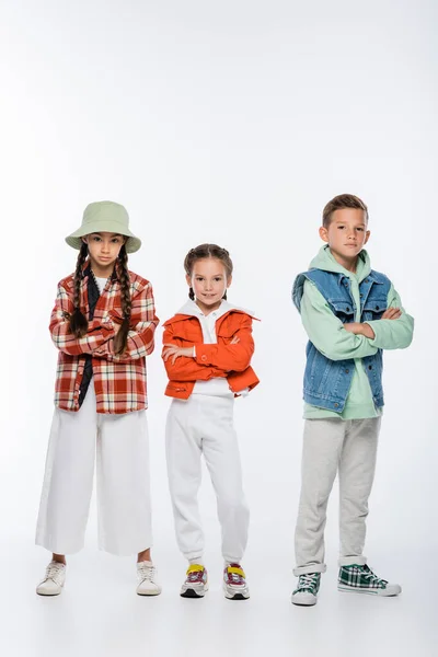 Full length of boy and stylish girls standing with crossed arms on white — Stock Photo